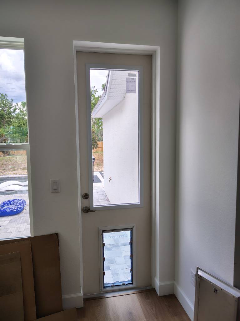 Interior view of new exterior door with built-in dog door and glass panel above